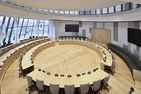 A view from above showing gray Intra chairs arranged in circular rows. There is a microphone at each seat. Along the edge are gray benches.