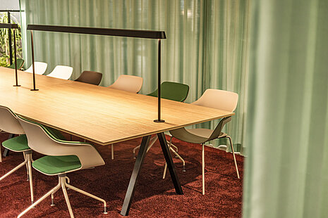 This is a close-up of a table setting with cream beige Occo chairs. The seat pads come in various colors, such as green, brown, and white. The whole scene is set against a light green curtain.