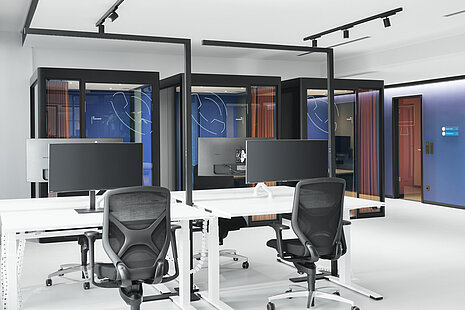 The modern open-plan workspace is furnished with IN swivel chairs, recognizable by their distinctive backrest design and synchronous movement mechanism. The clean lines and glass meeting pods create a futuristic, very uncluttered work environment. The chairs add functional, ergonomic accents to the space.
