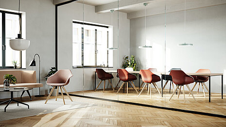 The meeting room is open, flooded with natural light, and features warm wooden accents. Surrounding the table are several Yonda chairs with wooden frames and red seat shells.