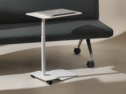 Confair Next side table on casters next to sofa, mobile workstation scene