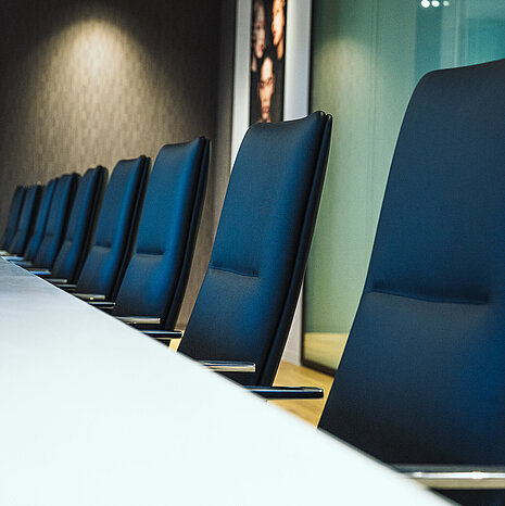 A close-up of Sola conference chairs in black leather. They are arranged around a white table in a conference room.