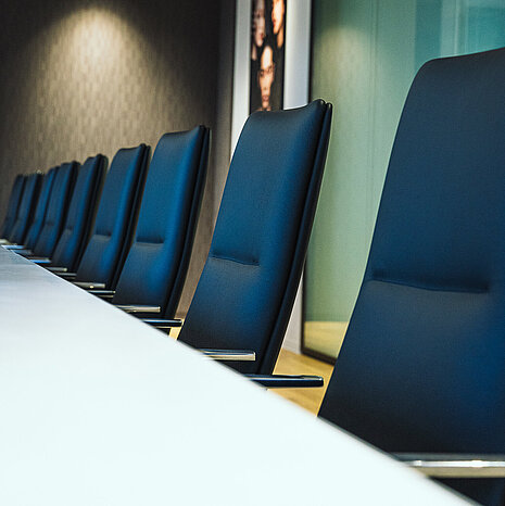 A close-up of Sola conference chairs in black leather. They are arranged around a white table in a conference room.