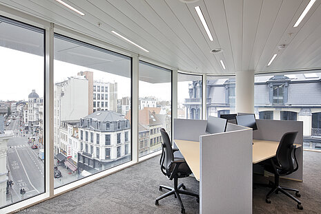 It is an office with a group of four tables, each with a black AT swivel chair in front of it.