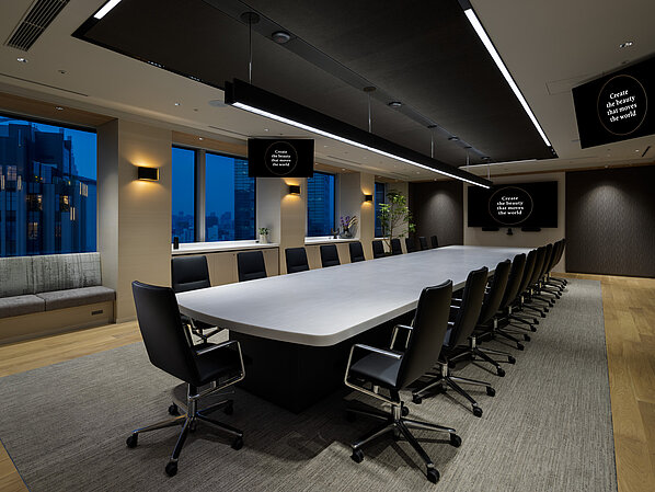 In a large conference room, several Sola conference chairs upholstered in black leather are arranged around a long table with a white tabletop.