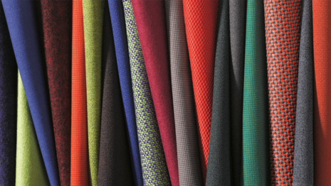 Various fabrics in a wide variety of colors are laid out side by side.