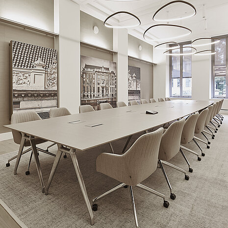 The photo shows a spacious, bright conference room with a long table and beige upholstered swivel chairs on casters. These are the Yonda conference chairs. The large, sculptural light fixtures and wall art give the room an elegant, modern touch.