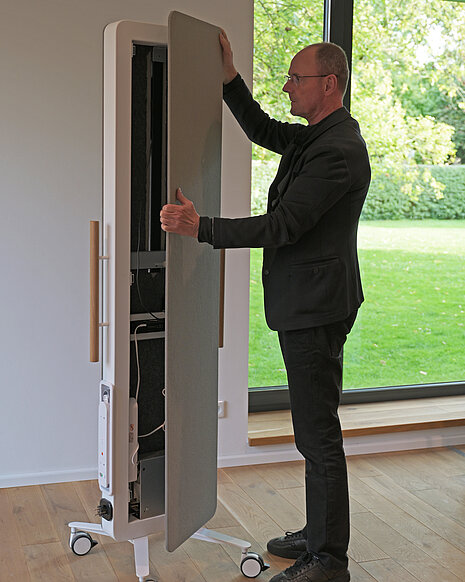 A person removes the front panel of the display rack to show how the technology is installed inside.