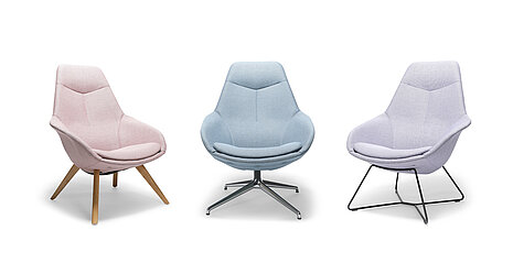 It is a photo with a white background showing three fully upholstered Yonda lounge chairs in three different colors: pastel pink, blue, and purple. The three chairs have different bases: a four-legged wooden base, a four-legged chrome base, and a cantilever base.
