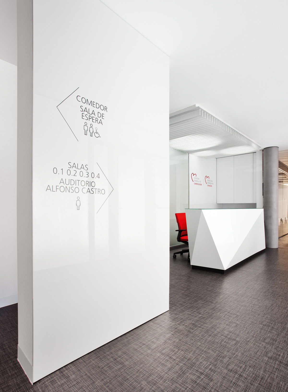 The foyer is dominated by white, red and black. Red, upholstered Neos office chairs (design: wiege) were placed behind the sculptural-looking reception counter.